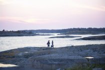 Vue latérale de deux femmes marchant sur des rochers le long de la mer — Photo de stock