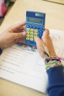 Schoolgirl holding calculator over study book — Stock Photo