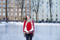 Donna in piedi sulla pista di ghiaccio e sorridente — Foto stock