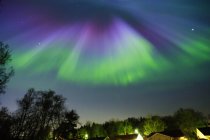 Residental building roof under aurora borealis illuminated sky — Stock Photo