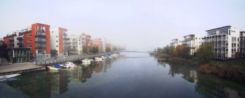 Panoramic view of buildings on riverbanks and moored boats — Stock Photo