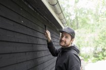 Мужчина рисует дом снаружи и смотрит в камеру — стоковое фото