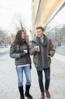 Homme et femme marchant dans la rue et tenant le café dans des tasses jetables — Photo de stock