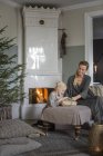 Mother and daughter sitting by fireplace opening Christmas presents — Stock Photo