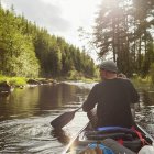 Visão traseira do homem remando canoa ao longo do rio — Fotografia de Stock
