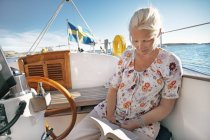 Mid adult woman sitting in boat and reading book — Stock Photo