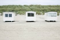Vue de face des cabanes blanches sur la plage de sable fin — Photo de stock