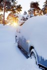 Vue avant de la voiture couverte de neige au coucher du soleil — Photo de stock