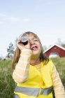 Girl looking through an magnifying glass, focus on foreground — Stock Photo