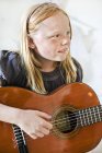 Mädchen mit blonden Haaren spielt Akustikgitarre — Stockfoto