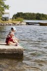 Вид сбоку на девочек, ловящих рыбу в озере, фокус на переднем плане — стоковое фото