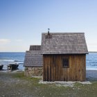 Pequena casa de madeira na praia sob o céu azul — Fotografia de Stock
