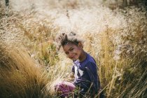 Портрет улыбающейся девушки, сидящей в поле — стоковое фото