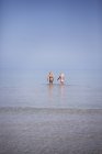 Две девушки, идущие по мелкому морю — стоковое фото