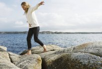 Side view of woman on rocks against sky with clouds — Stock Photo