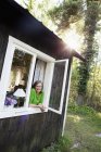 Frau blickt aus Fenster auf Wald — Stockfoto