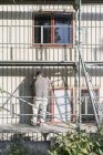 Man on scaffolding fixing siding on house — Stock Photo