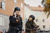 Couple standing with bicycles, woman using digital tablet, man talking on phone, selective focus — Stock Photo