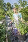 Senior woman holding bike in garden — Stock Photo