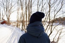 Вид сзади на человека, идущего в зимнем пейзаже — стоковое фото