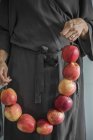 Mulher de vestido cinza segurando maçãs amarradas juntas — Fotografia de Stock