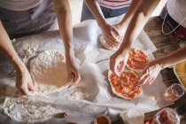 Women preparing homemade pizzas on table — Stock Photo