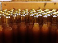 Бутылки без этикеток с закрытыми крышками и наполненные светло-коричневой жидкостью — стоковое фото