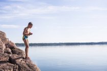 Junge steht auf Felsen und schaut auf Wasser — Stockfoto