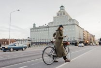 Woman looking over shoulder and cycling on city street — Stock Photo