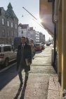 Businessman walking along city, focus on foreground — Stock Photo