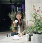 Улыбающаяся женщина сидит в кафе и пишет смс — стоковое фото