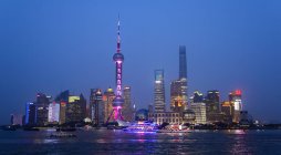 Finanzviertel in Shanghai mit Fluss Huangpu im Vordergrund nachts beleuchtet — Stockfoto