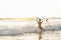 Adolescente con tabla de surf vadeando en el mar en Costa Rica - foto de stock