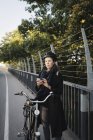 Молода жінка стоїть на велосипеді і використовує телефон — стокове фото
