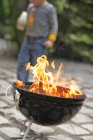 Focus sur barbecue avec garçon en arrière-plan — Photo de stock