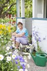 Mulher sentada na frente de inclinação da casa do jardim — Fotografia de Stock