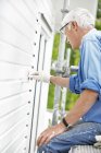 Side view of senior man painting wall — Stock Photo
