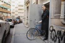 Junger Mann verlässt Haus mit Fahrrad — Stockfoto