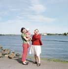 Retrato de madre, hija y abuela de pie contra el mar, enfoque en primer plano - foto de stock