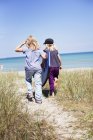 Dos chicas caminando en la playa a la luz del sol - foto de stock