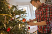 Man decorating Christmas tree at home — Stock Photo