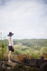Vista lateral da mulher de chapéu preto olhando para a paisagem — Fotografia de Stock