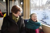 Девушка сидит с бабушкой в трамвае и смеется — стоковое фото