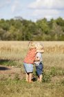 Side view of boy and girl hugging at meadow, differential focus — Stock Photo