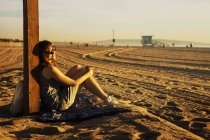 Вид сбоку женщины, сидящей на пляже — стоковое фото