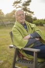 Portrait of senior man sitting in chair outdoors, focus on foreground — Stock Photo