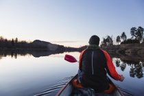 Rear view of man canoeing at sunset — Stock Photo