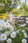 Женщина расслабляется за столом в саду с солнечным освещением — стоковое фото