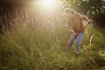 Вид сбоку на женщину, стригущую траву — стоковое фото