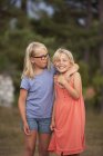 Mädchen in Brille umarmt Schwester, Fokus auf den Vordergrund — Stockfoto